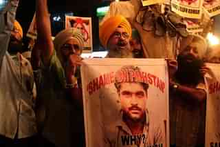 People shout slogans against Pakistan as they display photographs of Sarabjit Singh