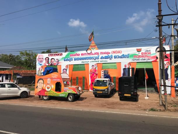 A BJP campaign vehicle in front of party posters and hoardings.