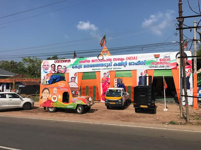 A BJP campaign vehicle in front of party posters and hoardings. 