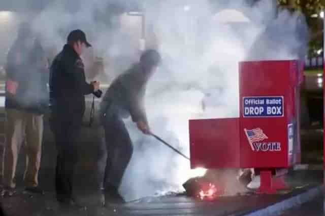 Officials putting out the fire on a ballot box in the USA