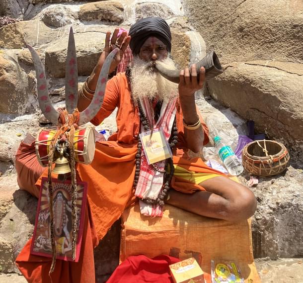 A Kali sadhaka bestowing his blessings while blowing the horn