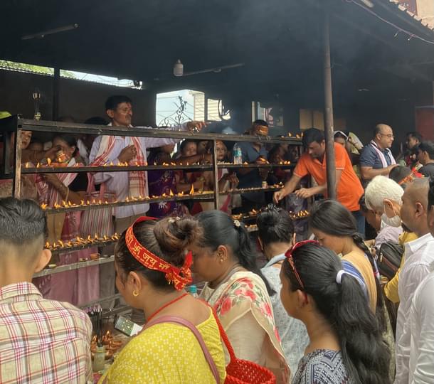 Some devotes, local and pilgrims, light diyas outside the temple.