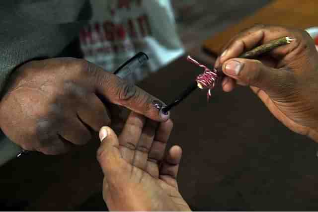 In an Indian Election , Electoral officer marking a stain on the voter 