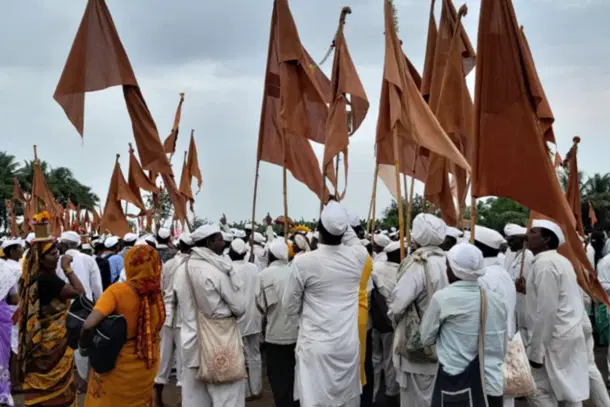 Pilgrims holding saffron flags in vari while walking on the road to Pandharpur.
