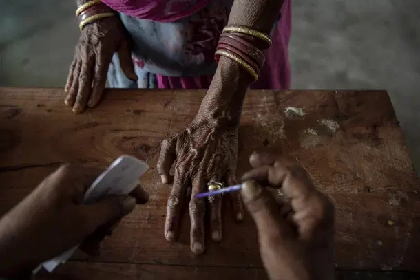 An Indian woman has her finger inked by an elections worker before voting at a polling station. (Kevin Frayer/Getty Images)