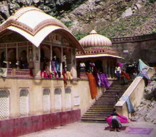 Galta kund with temple pavilions and women drying bright saris on the steps, the sacred valley where Jaipur begins.