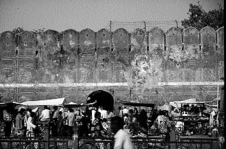 Section of Jaipur’s city wall with a small bazaar pressed against it, turning fortification into everyday street life.