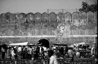 Section of Jaipur’s city wall with a small bazaar pressed against it, turning fortification into everyday street life.